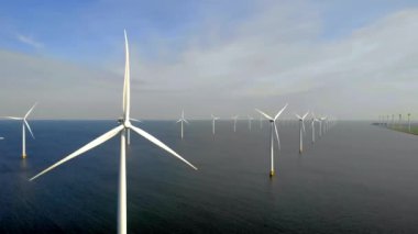 Bulutları ve mavi gökyüzü olan off-shore yel değirmeni parkı, rüzgar türbini Flevoland Hollanda 'nın deniz manzaralı yel değirmeni parkı Ijsselmeer. Yeşil enerji. 