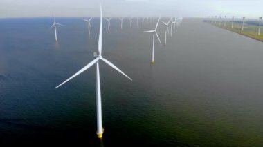 Bulutları ve mavi gökyüzü olan yel değirmeni parkı, okyanus manzaralı yeşil enerji rüzgar türbini Flevoland Hollanda Ijsselmeer ile yel değirmeni parkı..