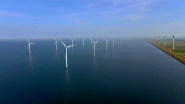 Bulutları ve mavi gökyüzü olan off-shore yel değirmeni parkı, rüzgar türbini Flevoland Hollanda 'nın deniz manzaralı yel değirmeni parkı Ijsselmeer. Yeşil enerji. 