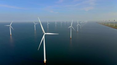 Bulutları ve mavi gökyüzü olan off-shore yel değirmeni parkı, rüzgar türbini Flevoland Hollanda 'nın deniz manzaralı yel değirmeni parkı Ijsselmeer. Yeşil enerji. 