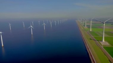 Bulutlu ve mavi gökyüzü olan yel değirmeni parkı, okyanus havası manzaralı rüzgar türbini Flevoland Hollanda Ijsselmeer