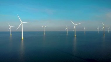 Bulutları ve mavi gökyüzü olan off-shore yel değirmeni parkı, rüzgar türbini Flevoland Hollanda 'nın deniz manzaralı yel değirmeni parkı Ijsselmeer. Yeşil enerji. 