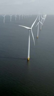 Kıyıdan uzak yel değirmeni parkı ve denizde mavi bir gökyüzü, okyanusta rüzgar türbini Flevoland Hollanda 'nın deniz manzaralı yel değirmeni parkı Ijsselmeer