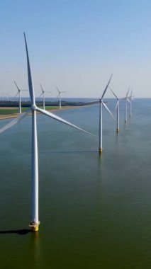 Bulutlu ve mavi gökyüzü olan yel değirmeni parkı, okyanus havası manzaralı rüzgar türbini Flevoland Hollanda Ijsselmeer