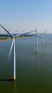 Bulutlu ve mavi gökyüzü olan yel değirmeni parkı, okyanus havası manzaralı rüzgar türbini Flevoland Hollanda Ijsselmeer