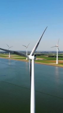 Bulutlu ve mavi gökyüzü olan yel değirmeni parkı, okyanus havası manzaralı rüzgar türbini Flevoland Hollanda Ijsselmeer