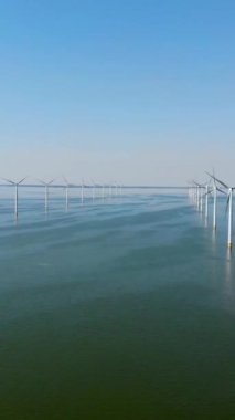 Bulutlu ve mavi gökyüzü olan yel değirmeni parkı, okyanus havası manzaralı rüzgar türbini Flevoland Hollanda Ijsselmeer