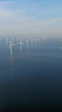 Açık deniz yel değirmeni parkı bulutlu ve mavi gökyüzü, okyanus havası manzaralı rüzgar türbini Flevoland Hollanda Ijsselmeer güneşli bir günde