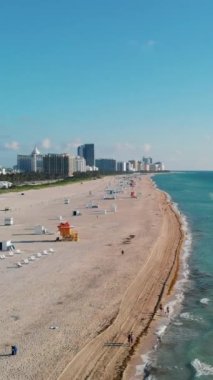 Miami South Beach Florida 'da. Güneşli bir günde renkli sandalyeler, şemsiyeler ve cankurtaran kulübesi olan plaj.