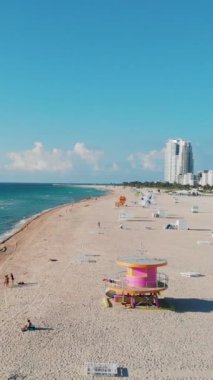 Miami South Beach Florida 'da. Renkli sandalyeleri, şemsiyeleri ve güneşli bir günde cankurtaran kulübesi olan renkli tropikal plajlar.