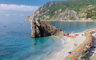 Çakıl taşı plajı Monterosso tatili Cinque Terre Monterosso al Mare sandalyeleri ve şemsiyeler yaz boyunca Cinque Terre İtalya 'nın bir parçası olan Spiaggia di Fegina plajını dolduruyor.