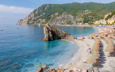 Pibble Beach Monterosso tatili Cinque Terre Monterosso al Mare Sandalyeleri ve şemsiyeleri Cinque Terre İtalya 'nın bir parçası olan Spiaggia di Fegina plajını dolduruyor.. 