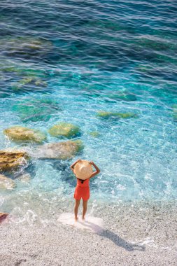 Asyalı kadınlar Monterosso Cinque Terre İtalya 'nın bir parçası olan Monterosso' nun çakıl taşı plajını, Mare Spiaggia di Fegina sahilindeki sandalyeleri ve şemsiyeleri ziyaret ediyorlar.. 