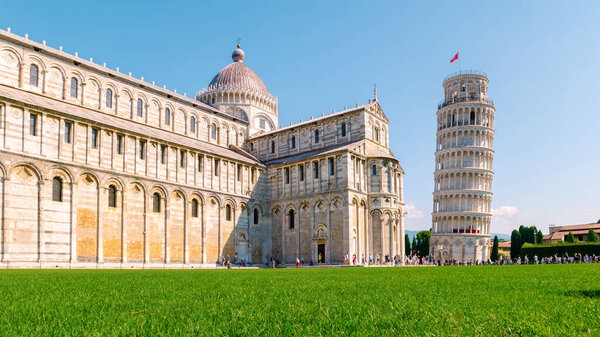 Leaning tower of Pisa, Italy with Basilica and Cathedral on a bright summer day with green grass low angle. 