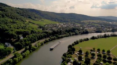 Bernkastel dağlarında, aydınlık bir yaz gününde, Almanya 'daki Moselle nehri üzerinden iç kesimlere doğalgaz nakliyesi. Yaz boyunca Mosel nehrinde, dağlarda üzüm bağları olan bir gaz tankeri.