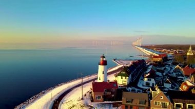 Urk deniz fenerinde kar yağışı Ijsselmeer Gölü 'nün kayalık sahilinde eski ada Urk Flevoland Hollanda' da günbatımında