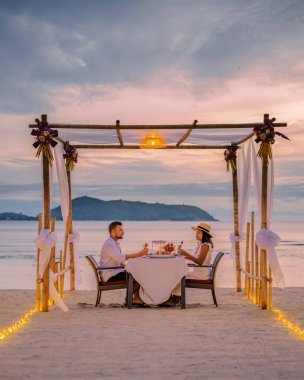 Çiftler gün batımında Phuket Thailand sahilinde romantik bir akşam yemeği yiyorlar. 