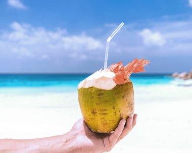 Seyşeller 'de beyaz tropikal bir plajda hindistan cevizi, erkeklerin elinde hindistan cevizi.. 