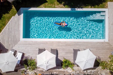 Oteldeki havuzda iki kişi yüzüyor. Yukarıdan bakıldığında, birkaç erkek ve kadın Fransa 'da lüks bir tatil evinde yüzüyorlar.