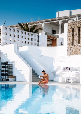 Havuzda kısa yüzen gençler yaz boyunca Yunanistan 'da tatil hakkında bir kitap okuyorlar.