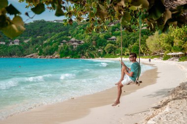 Seyşeller tropikal adası, beyaz sahildeki genç adam Tatil boyunca Mahe Seyşeller