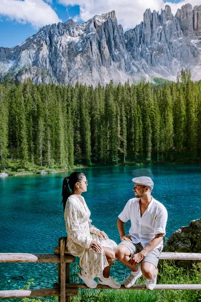 the couple visits the bleu lake in dolomites Italy, Carezza lake Lago di Carezza, Karersee with Mount Latemar, Bolzano province, South Tyrol, Italy.