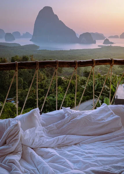 Phangnga Bay Thailand, outside bed with pillow and bedsheet looking out over the bay, honeymoon vacation Thailand at sunset