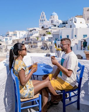 Santorini Yunanistan 'da tatilde olan bir çift, iki erkek ve kadın Oia Santorini' yi boyalı binalarla ziyaret ediyor. Santorini Yunanistan 'da, Pyrgos köyünde