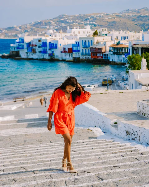 Mykonos Greece, Young woman in a red dress on the Streets of old town Mikonos during a vacation in Greece, Little Venice Mykonos Greece.
