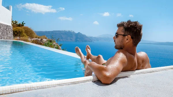 Santorini Greece Oia 若い男性で泳ぐショートパンツプールでリラックスしているSantorini島のカルデラを見下ろすギリシャ インフィニティプール ヨーロッパでの豪華な休暇に若い男ギリシャ — ストック写真