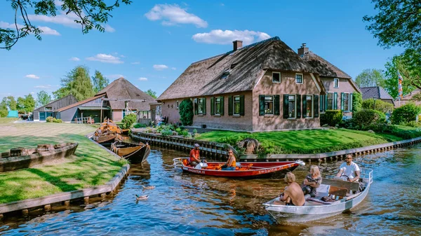GIETHOORN, NETHERLANDS Mayıs 2020 tipik evler ve turistler Giethoorn, Hollanda 'da renkli elektrikli tekneler. Güzel evler ve bahçıvanlık şehri Avrupa 'nın kuzeyindeki Venedik olarak bilinir.