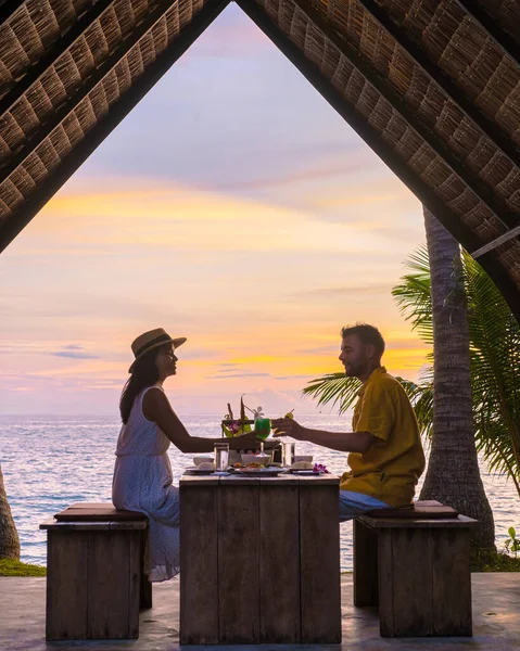 プーケット島での日没時にタイ料理とビーチでロマンチックなディナータイ ビーチでロマンチックなディナーをしている男女のカップル — ストック写真