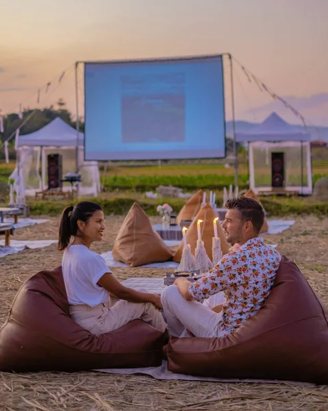 people looking at movies at outdoor cinemas at night in the countryside of Northern Thailand., outdoor movie film, couples watching movies outside on a screen