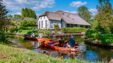 GIETHOORN, NETHERLANDS Mayıs 2020 Hollanda 'daki Giethoorn turistlerinin tipik evleri görülüyor. Güzel evler ve bahçıvanlık şehri Avrupa 'nın kuzeyindeki Venedik olarak bilinir.