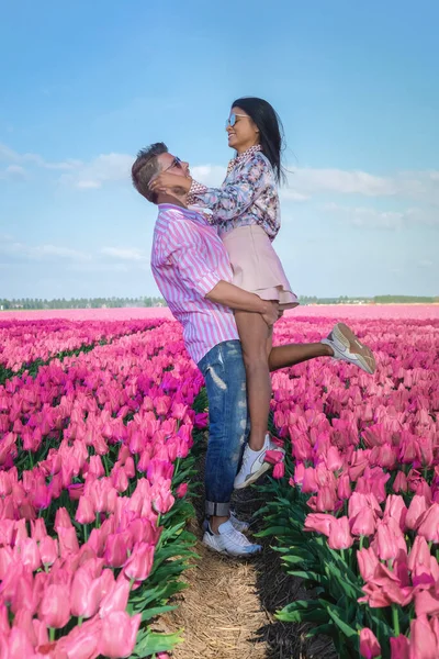 A couple of men and women in a tulip field, red tulips during the Spring season in the Netherlands Europe, men and women visit a flower field with tulips