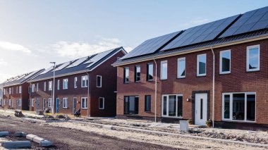 Çatıya güneş panelleri takılı yeni evler güneşli bir gökyüzüne karşı, siyah güneş panelleri olan yeni binalar. Zonnepanelen, Zonne Energie, Çevirisi: Güneş enerjisi. Konut piyasası