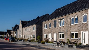 Çatıda güneş panelleri olan yeni evler güneşli bir gökyüzüne karşı, siyah güneş panelleri olan yeni binalar. Zonnepanelen, Zonne Energie, Çevirisi: Güneş enerjisi. Hollanda