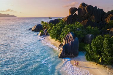 Anse Source dArgent, La Digue Seychelles, Seyşeller 'de lüks bir tatil sırasında tropikal bir plajda yaşayan genç bir çift. Tropik sahil Anse Kaynak dArgent, La Digue Seyşeller