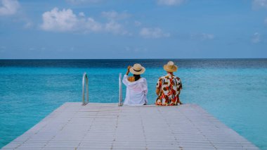 Bir çift Playa Porto Marie plajı Curacao 'yu ziyaret ediyor. Turkuaz suyu okyanusu olan beyaz tropikal plaj. Curacao' da tatilde olan birkaç erkek ve kadın.