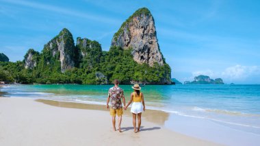 Railay Beach Krabi Tayland, Railay Krabi 'nin tropikal plajı, kumsalda bir çift kadın ve erkek, Tayland' da geleneksel uzun bir teknesi olan huzurlu Railay Kumsalı manzarası..