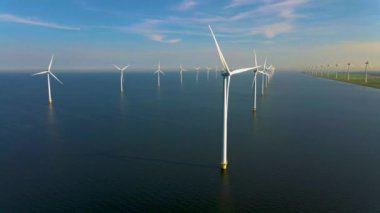 Bulutlu ve mavi gökyüzü olan yel değirmeni parkı, okyanus havası manzaralı rüzgar türbini Flevoland Hollanda Ijsselmeer