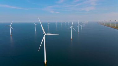 Rüzgar türbinlerinin insansız hava aracı görüntüsü, bulutlu ve mavi gökyüzü olan yel değirmeni parkı, okyanus havası manzaralı rüzgar türbini Flevoland Hollanda Ijsselmeer ile yel değirmeni parkı.