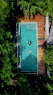Havuzdaki çift, Krabi Tayland ormanındaki bir yüzme havuzunun havadan drone görüntüsü, Tayland ormanında yüzme havuzunun üstünde bir dron. Bilardoda bir çift kadın ve erkek. 