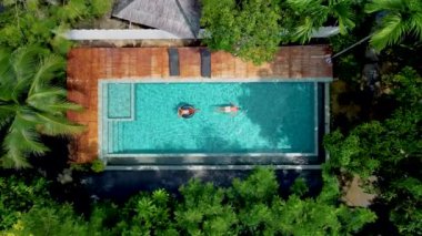 Havuzdaki çift, Krabi Tayland ormanındaki bir yüzme havuzunun havadan drone görüntüsü, Tayland ormanında yüzme havuzunun üstünde bir dron. Bilardoda bir çift kadın ve erkek. 
