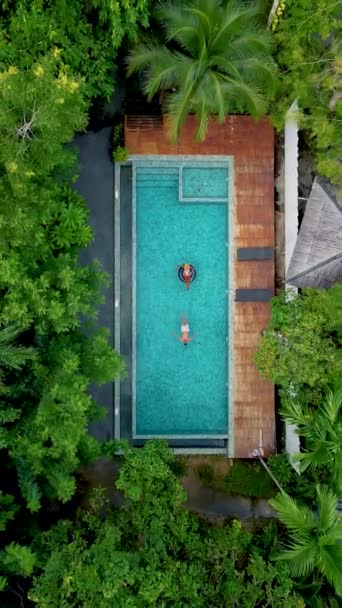 プールのカップル クラビタイのジャングルの中のスイミングプールの空中ドローンビュー タイのジャングルの中のスイミングプールの上のドローンとの空中ビュー プールにいる男女のカップルは — ストック動画