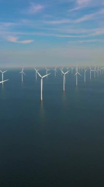 Denizdeki yel değirmeni türbinlerinin drone görüntüsü, bulutlu ve mavi gökyüzü olan yel değirmeni parkı, okyanus havalimanı manzaralı rüzgar türbini Flevoland Hollanda Ijsselmeer