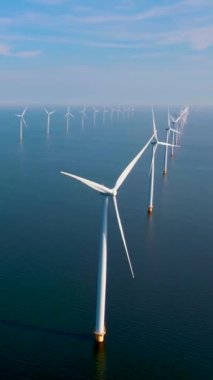 Denizdeki rüzgar türbinlerinin insansız hava aracı görüntüsü, bulutlu ve mavi gökyüzü olan yel değirmeni parkı, okyanus havası manzaralı rüzgar türbini Flevoland Hollanda 'daki Ijsselmeer.