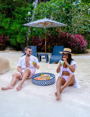 Tayland 'da küçük bir plajda havuz kenarında atıştırmalık ve kokteylleri olan bir çift. Erkekler ve kadınlar yüzme havuzunda tatildeler.