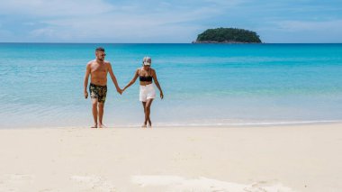 Tatil sırasında Kata Phuket Tayland sahilinde yürüyen bir çift.