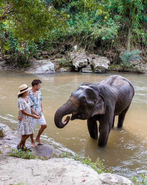 A couple visiting an Elephant sanctuary in Chiang Mai Thailand, an Elephant farm in the mountains jungle of Chiang Mai Thailand.